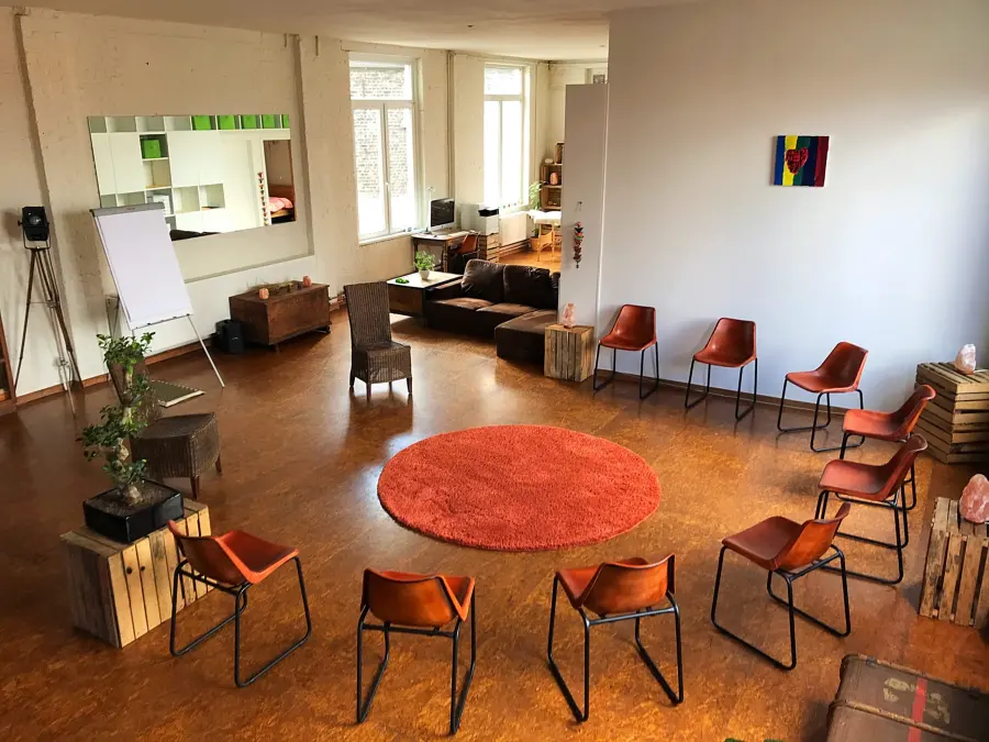 Een kring van stoelen rond een rond tapijt in een lichte ruimte